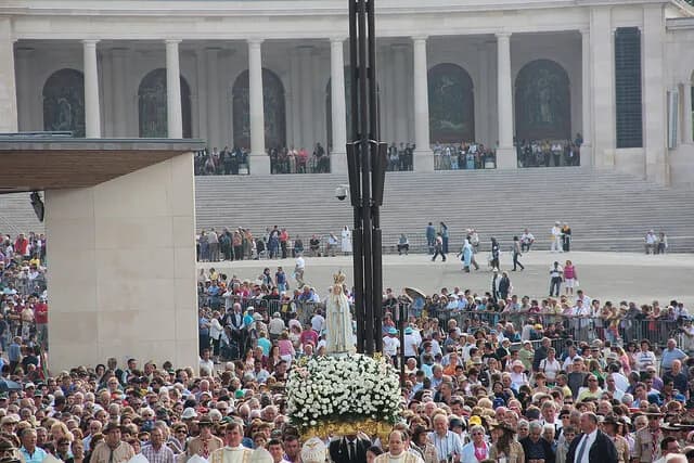 Crianças a oferecer flores a uma imagem de Nossa Senhora durante uma celebração tradicional no mês de maio.