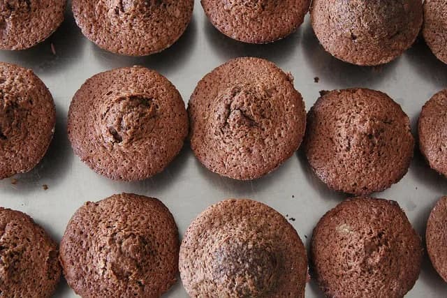 Bolo de chocolate fofo acabado de sair do forno sobre uma mesa de madeira.