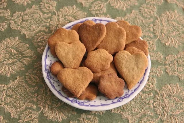 Prato com bolachas de canela caseiras acabadas de sair do forno numa mesa rústica.