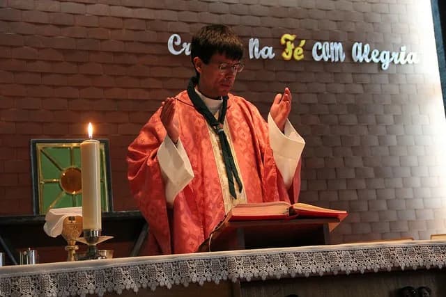 Jovem escuteiro no momento da sua promessa, rodeado pela patrulha e chefia num ambiente de celebração cristã.
