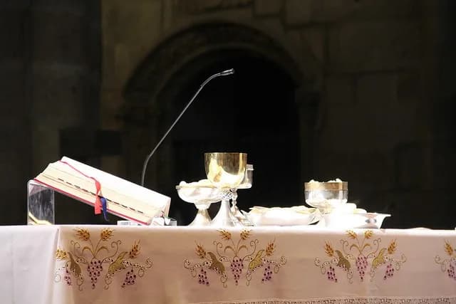 Uma coroa do Advento com duas velas acesas sobre o altar de uma igreja católica.
