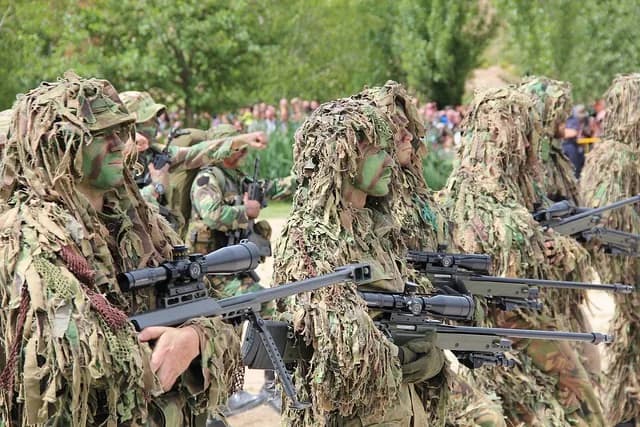 Um presépio improvisado com ramos de palmeira num altar militar rodeado por soldados de camuflado.