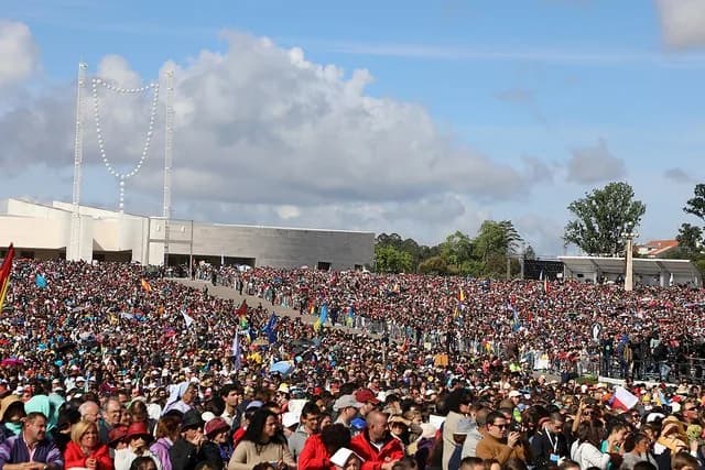 Milhares de peregrinos reunidos no Santuário de Fátima durante as celebrações do Centenário com velas acesas.