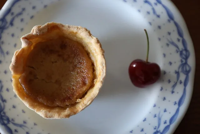 Pastéis de nata de cereja polvilhados com canela e açúcar, destacando a cor vibrante do fruto do Fundão.