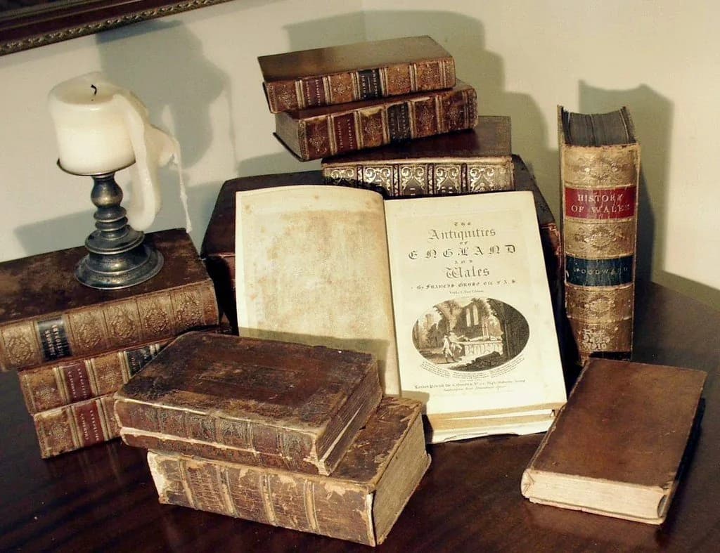 Um livro antigo aberto sobre uma mesa de madeira rústica, simbolizando a sabedoria e a companhia espiritual através dos tempos.