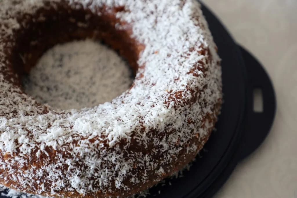 Bolo de coco fofinho polvilhado com coco ralado e servido numa travessa de loiça tradicional em Trancoso.