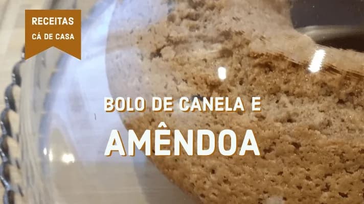 Fatia de bolo de canela e amêndoa polvilhado com açúcar num prato de porcelana branca.